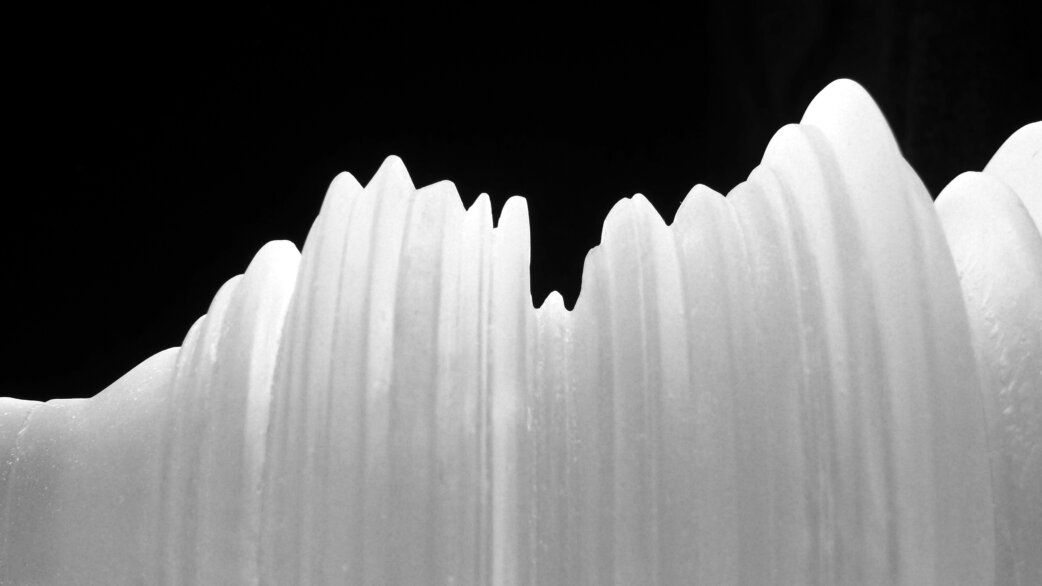 Glass sculpture depicting stock exchange data as undulating white ridges against a black background, with peaks and valleys representing market fluctuations including the 2009 crash.