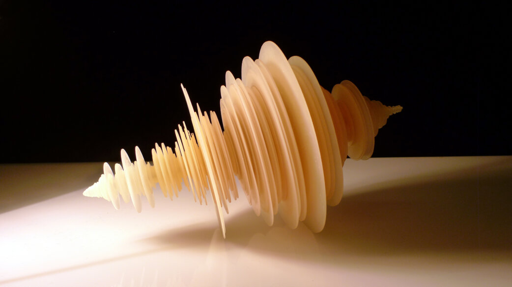 A cream-coloured 3D-printed sculpture resembling a spiralling waveform, created from rotated seismogram data of the 2011 Tōhoku earthquake, measuring approximately 30cm long, displayed against a black background.